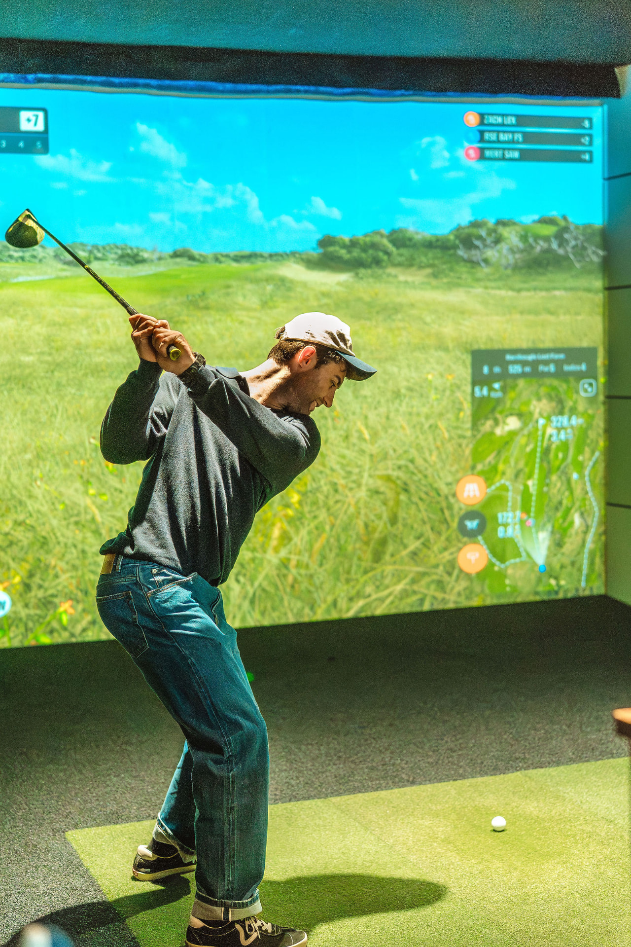 Player mid-backswing in a GolfSpace simulator bay