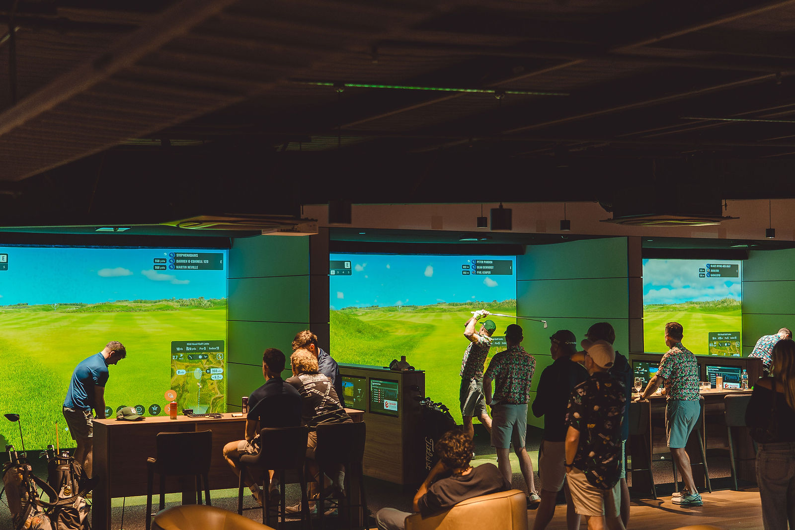 The full floor of GolfSpace simulator bays with teams playing and socialising
