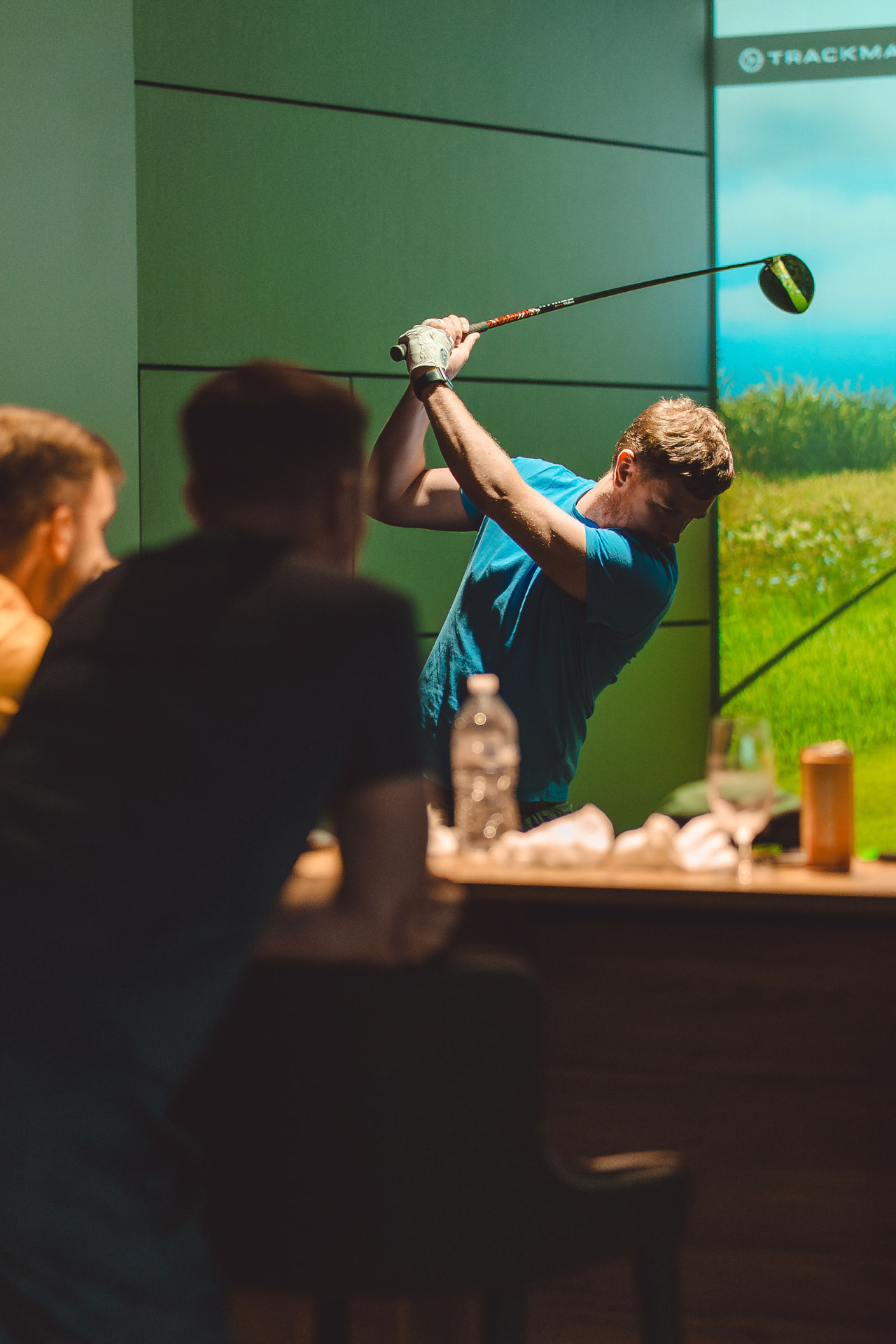 Teeing off while teammates watch from the bar counter