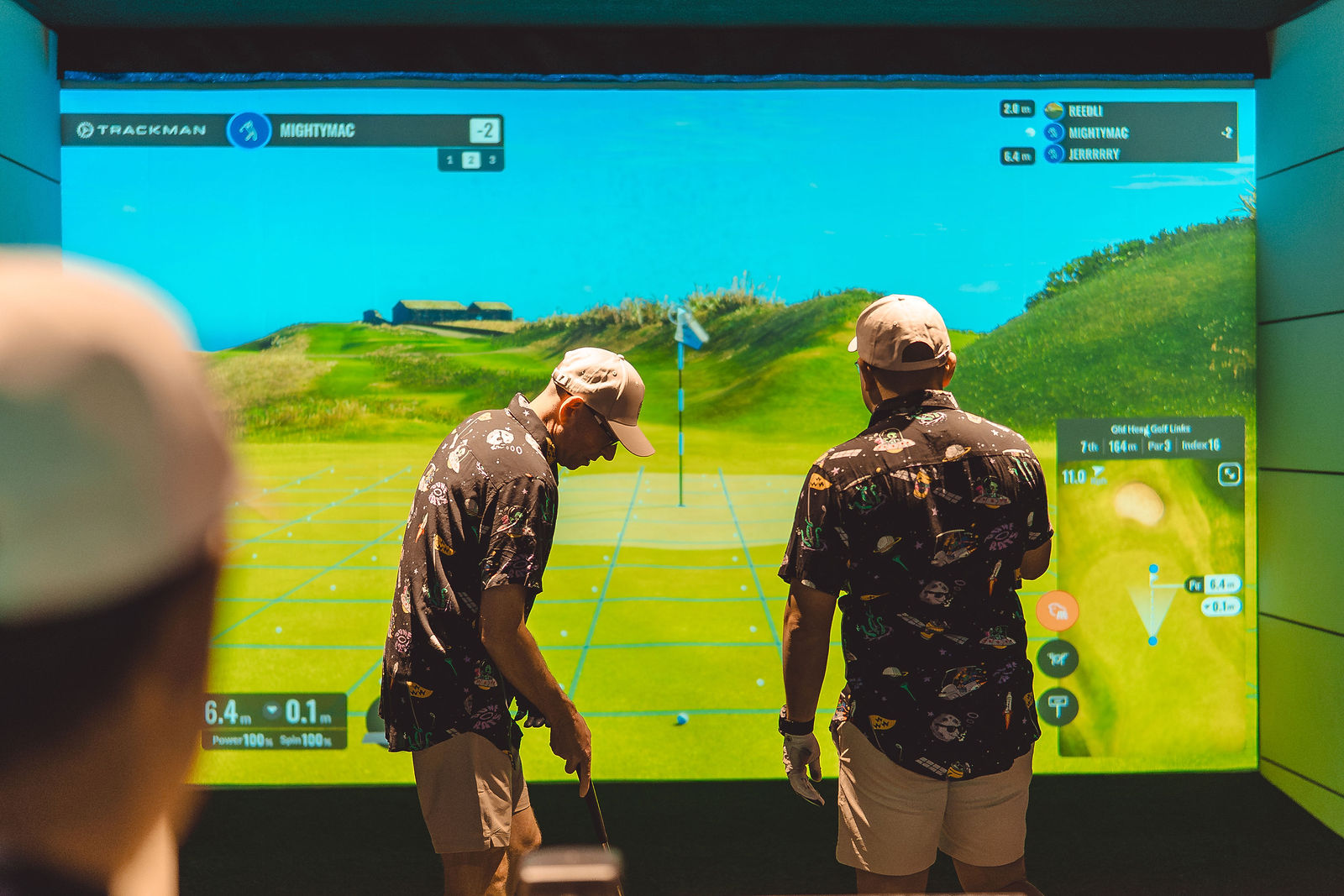 Two players reading a putt on the simulator screen
