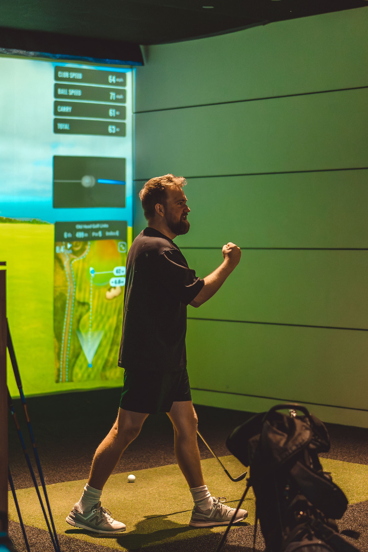 Player celebrating a shot with a fist pump in a simulator bay